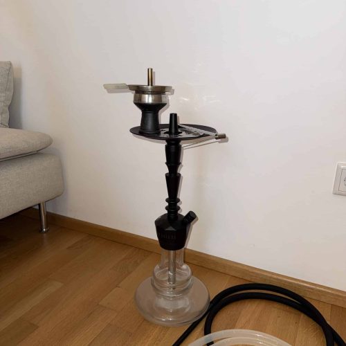 Shisha-Kopf mit Glasbowl und Schlauch auf Holzboden.