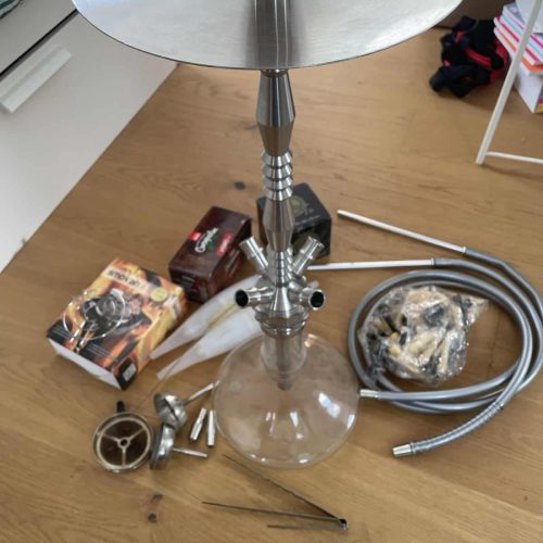 Komplettes Shisha-Raucherset mit Glas, Metall und Zubehör auf Holz.