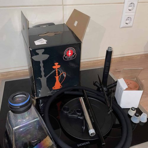 Shisha mit Zubehör auf einer Küchenarbeitsplatte, inklusive Verpackung und Ersatzteile.