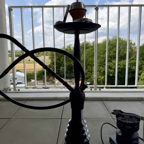 Schwarze Shisha mit Glasbowl auf Balkon mit Blick ins Freie.