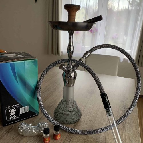 Rauch-Hookah mit Glasbasis, Schlauch und Tabakdosen auf Tisch.