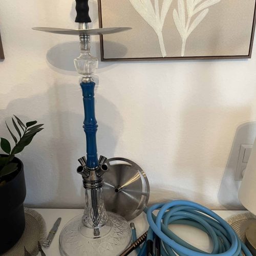 Hookah mit blauer Silikonschlauch und Zubehör, auf Tisch.