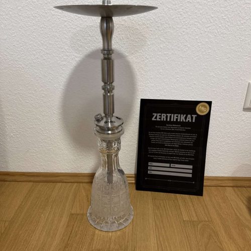 Wasserpfeifen-Kopf mit Glasbasis auf Holztisch, Zertifikat im Hintergrund.