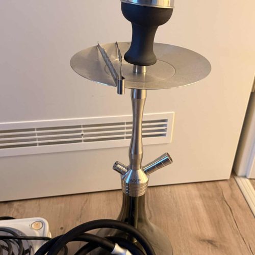 Shisha mit Glasbowl, Schlauch und Metallstück, auf Boden stehend.
