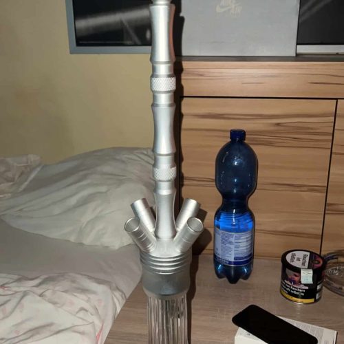 Hookah mit Glasbasis, Zubehör und Wasserflasche auf Nachttisch.