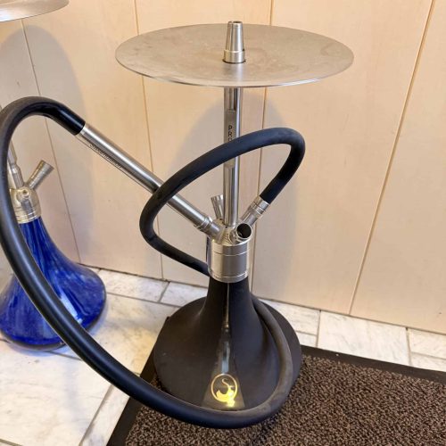 Shisha mit Glasbowl, Metall- und Silikonschlauch, auf Teppich.