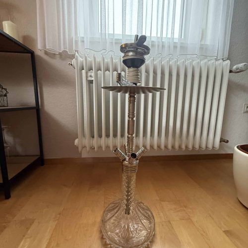 Rauch-Hookah mit Glasbasis vor Heizkörper im Raum.