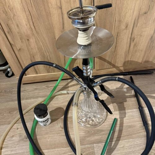 Shisha mit Glasbowl, Schlauch und Zubehör auf Holzboden.