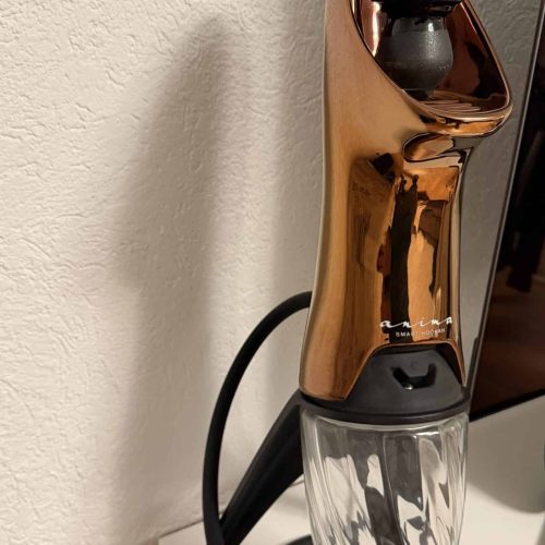 Luftbefeuchter mit Wasserbehälter und modernem Design, steht auf einem weißen Möbelstück.