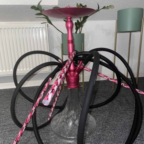 Shisha mit pinkem Kopf und Schläuchen auf Tisch.