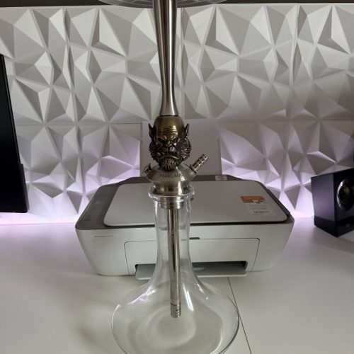 Moderne Shisha mit Glasbowl und Metallrohr auf weißem Tisch.
