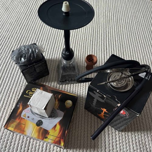 Verschiedene Shisha Teile inklusive Glasbowl, Schlauch und Kohle.