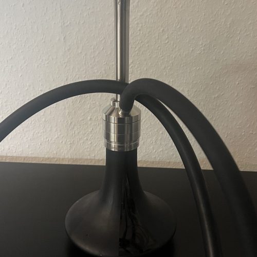 Shisha-Kopf mit Metallaufsatz und Schlauch, auf schwarzem Tisch.