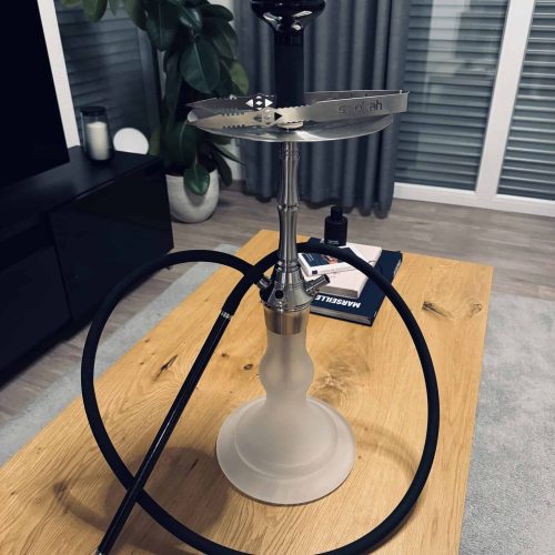 Rauchsäule mit Glasbowl, Schlauch und Zange auf Holztisch.