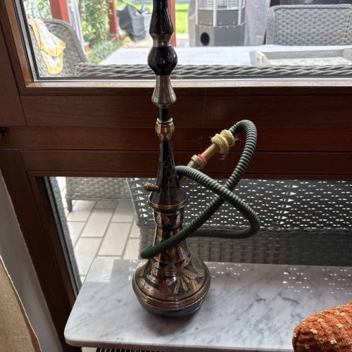 Raucherset für Shisha, inklusive Schlauch und Kopf, auf Fensterbank im Innenraum.
