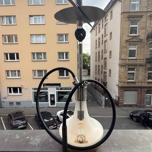 Shisha mit Glasbowl und Silikonschlauch auf Balkon, Blick auf Stadt und Parkplätze.