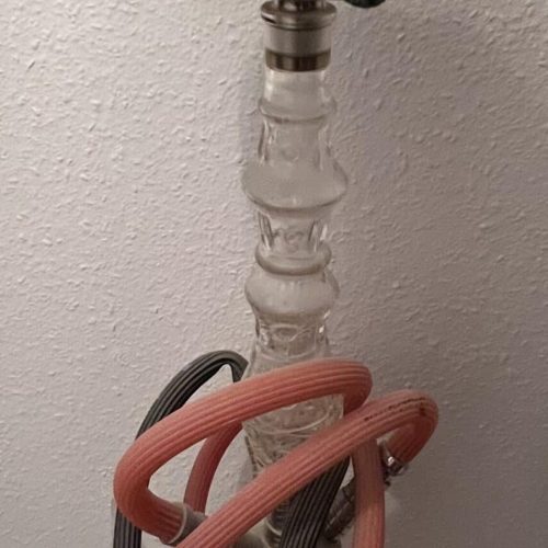 Shisha mit Glasbowl, Schlauch und Kopf, auf einer Wandmontage.