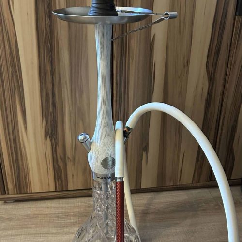 Shisha mit Glasbowl, Metallaufsatz und Schlauch, auf Holztisch.