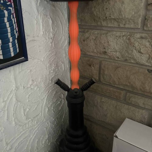 Rauch-Hookah auf dem Boden, mit schwarzer Basis, orangeem Mittelstück und Schale oben.