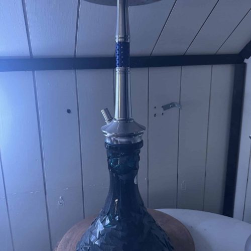 Shisha mit Glasbowl, Metallrohr und Schlauch, auf Holzunterlage.
