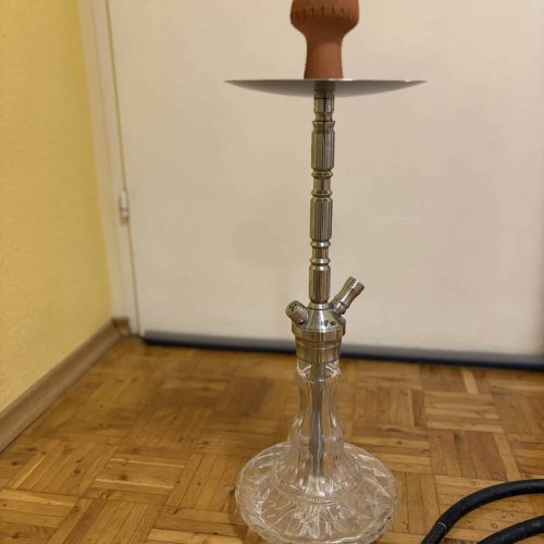 Rauch-Hookah mit Glasbasis, Holzaufsatz und Metallstange, auf Holzboden stehend.