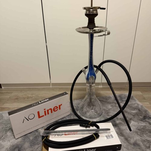 Shisha-Kopf mit Glasbowl, Schlauch und Zubehör, auf Teppich.
