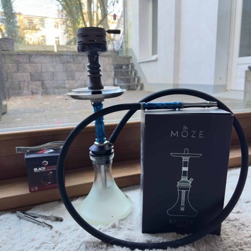 Rauchsäule mit Shisha, Kohlezange und Zubehör auf Fensterbank.
