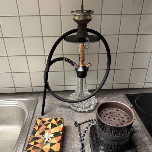 Shisha mit Glasbowl, Kohleofen und Zubehör auf Küchenarbeitsplatte.