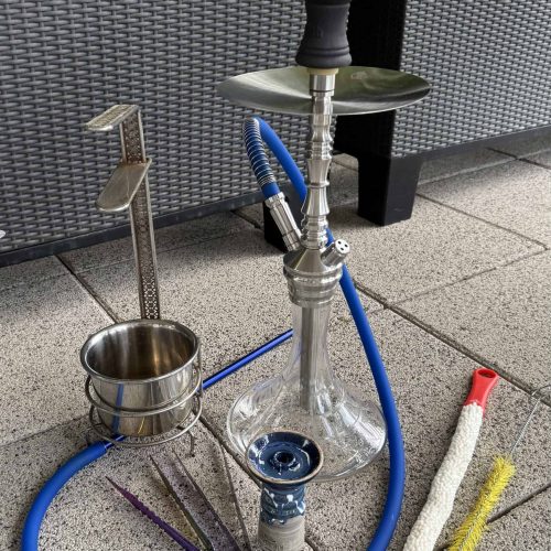 Shisha mit Glasbowl, Schlauch und Reinigungsbürsten im Freien.
