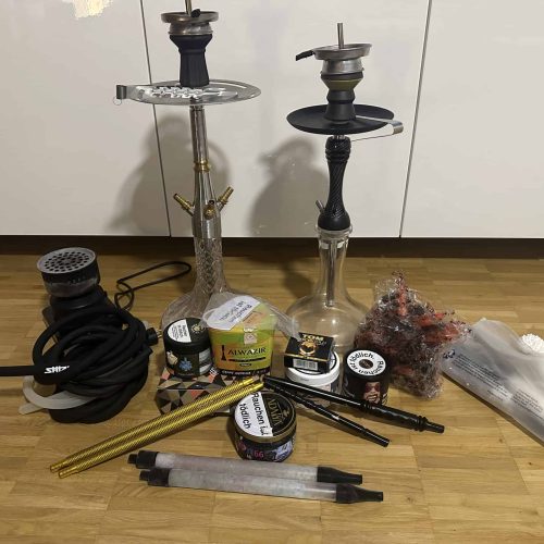 Zwei Shisha-Köpfe, Schlauch, Tabak, Zange und weiteres Zubehör.