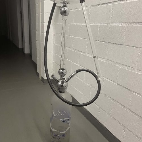 Rauchvorrichtung mit Flasche und Schlauch, vermutlich für Wasserpfeife oder ähnliches, steht an eine.