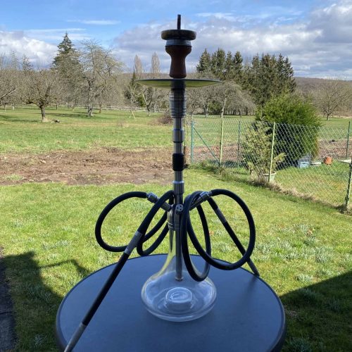 Rauchsäule mit Wasserpfeife auf einem Tisch im Garten, ideal für gemütliche Abende.