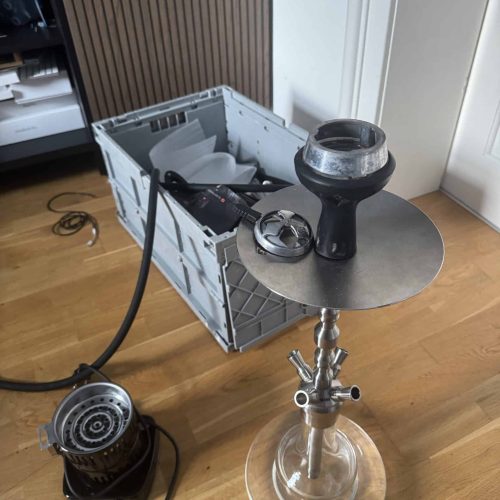 Shisha mit Rauchsäule und Zubehör auf Tisch, Indoor.