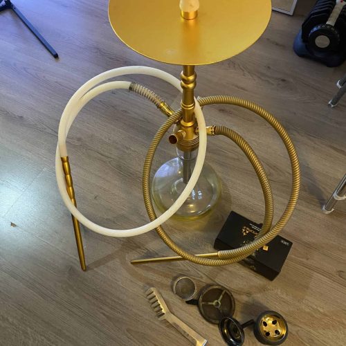 Goldenes Shisha-Raucherset mit Glasbowl und Zubehör, auf Holzboden.