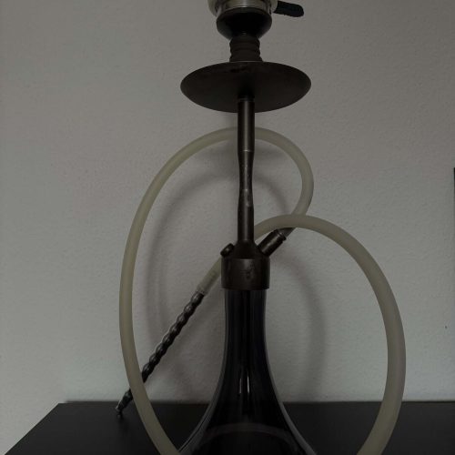 Shisha-Kopf mit Glasbowl und Schlauch, auf schwarzem Tisch.