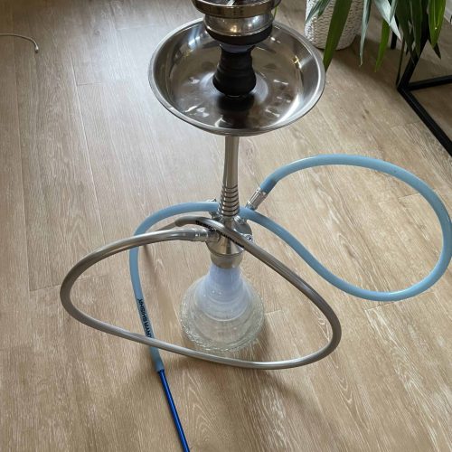 Rauchsäule mit Wasserpfeife, Schlauch und Metalltablett auf Holzboden.