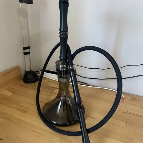 Rauchsäule mit Schlauch und Kopf für Shisha, auf Holztisch im Raum.