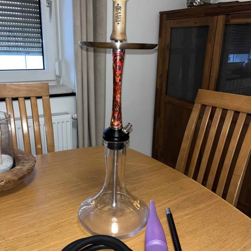 Rauchsäule mit Shisha-Kopf, Schlauch und Zubehör auf einem Holztisch. Perfekt für gemütliche Abende.