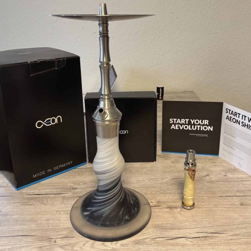 AEON Shisha mit Zubehör und Verpackung auf Holztisch.