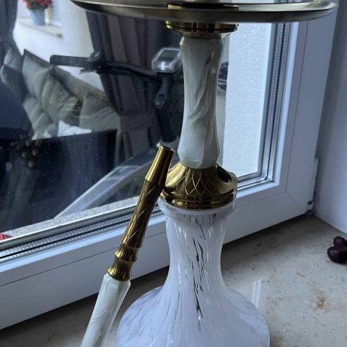 Hookah Wasserpfeife mit weißem Glas und goldenen Akzenten, auf Fensterbank stehend.