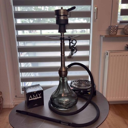 Shisha mit Glasbowl, Schlauch und Kohleanzünder auf Tisch.