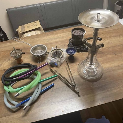Shisha mit Zubehör und Schläuchen auf Tisch, für Raucherlebnis.