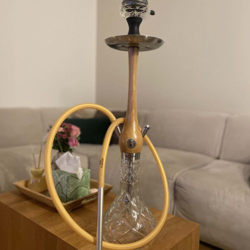 Shisha mit Glasbowl und Silikonschlauch auf Holztisch.