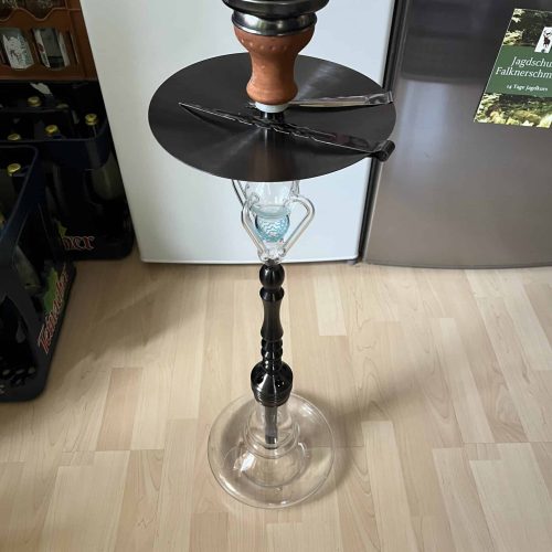 Hookah mit Glasbasis, Tabakschale und Zubehör, auf Holzboden.