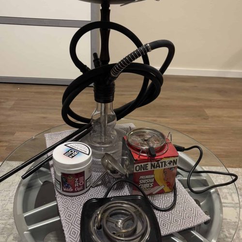Rauchsäule mit Shisha, Heizgerät und Tabak auf runden Tisch.