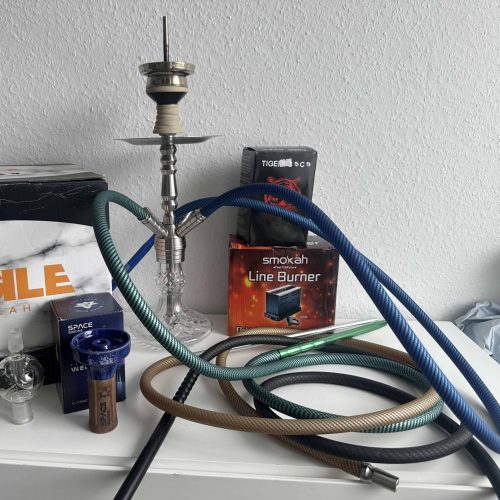 Shisha mit mehreren Schläuchen und Zubehör auf Tisch.