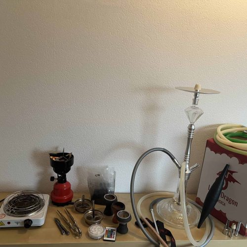 Shisha mit Zubehör und Heizgerät auf Tisch.
