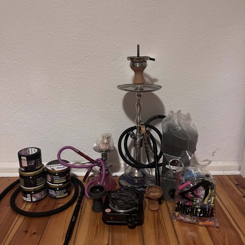 Shisha mit Zubehör, Tabak und Kohle auf Holztisch.
