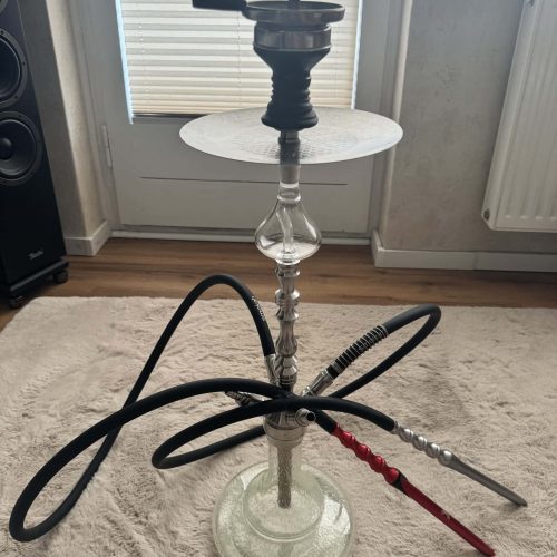 Shisha-Kopf mit Glasbowl, Schlauch und Tabakkopf, auf Teppichboden.