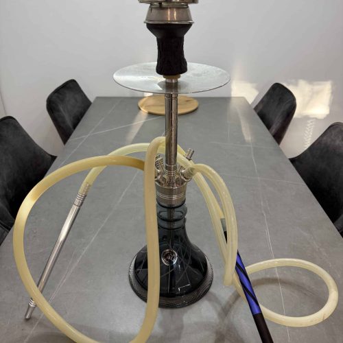 Shisha mit Glasbowl, Schlauch und Schlauchanschluss auf Tisch.